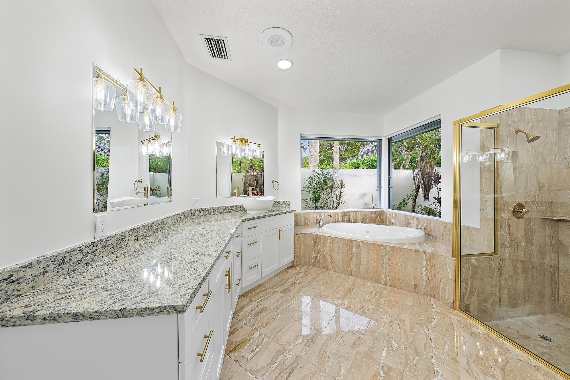 19558 Red Gum Trail Jupiter, FL 33458 - Photo 18 of 34 a spacious bathroom with a granite countertop tub shower and sink