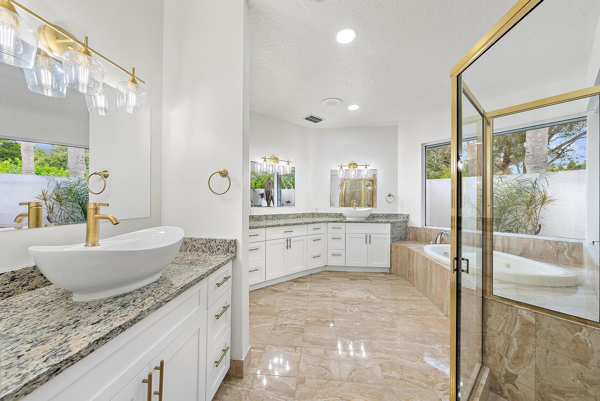 19558 Red Gum Trail Jupiter, FL 33458 - Photo 19 of 34 a large bathroom with a granite countertop double vanity sink a mirror and a bathtub