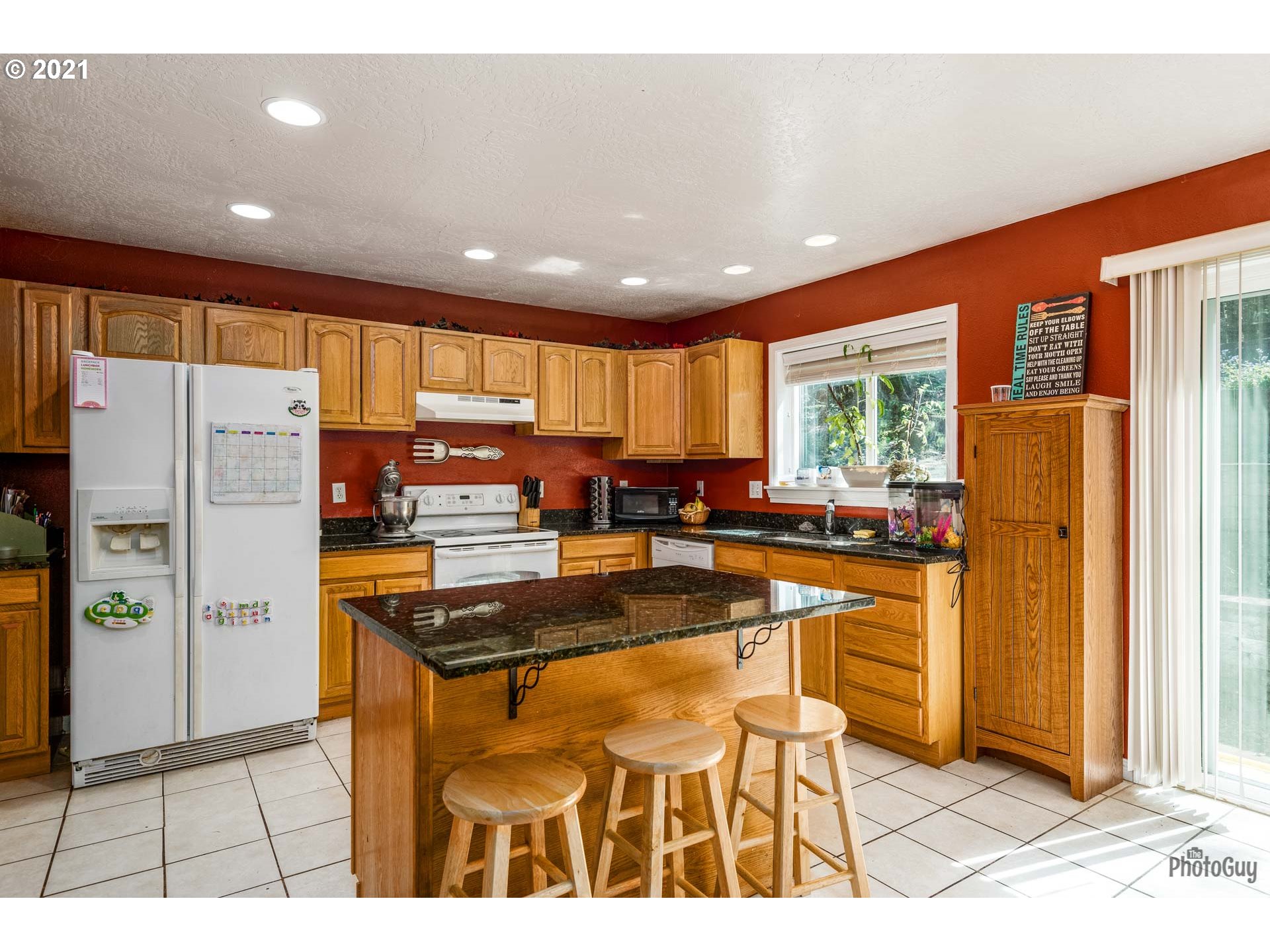 7277 Forsythia Street Springfield, OR 97478 - Photo 12 of 29 a kitchen with stainless steel appliances granite countertop a refrigerator a stove a sink dishwasher and a dining table with wooden cabinet