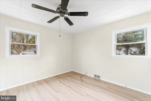 an empty room with a window and ceiling fan