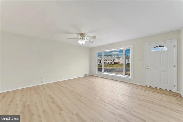 a view of an empty room with a window and wooden floor