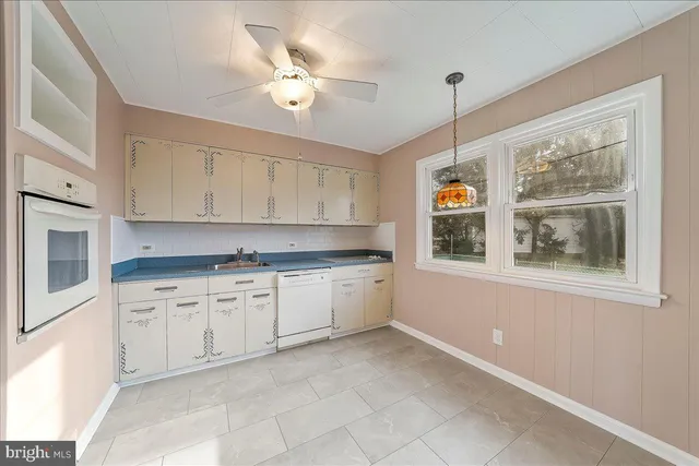 a kitchen with granite countertop white cabinets white appliances with a large window and sink