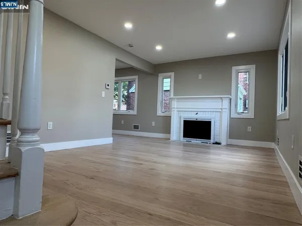 a view of empty room with wooden floor and fireplace