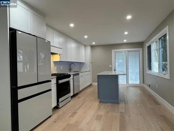 a kitchen with stainless steel appliances granite countertop a refrigerator a sink a stove and a wooden floors