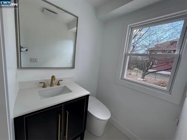 a bathroom with a sink vanity mirror and toilet