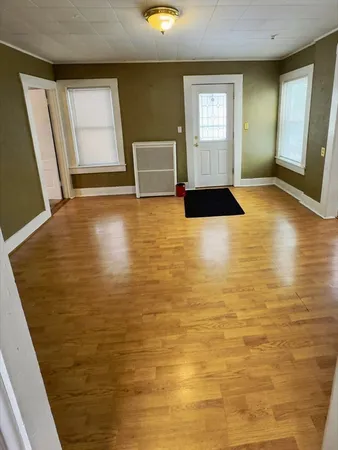 a view of empty room with window and wooden floor