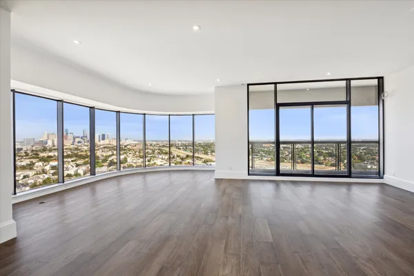 an empty room with wooden floor and large windows