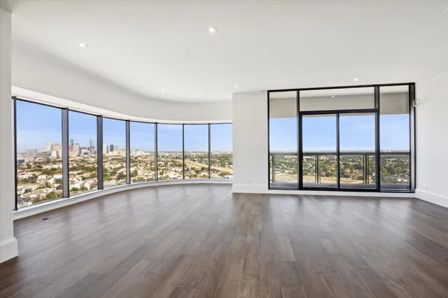 an empty room with wooden floor and large windows
