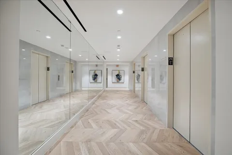 a view of a hallway with wooden floor and a bathroom