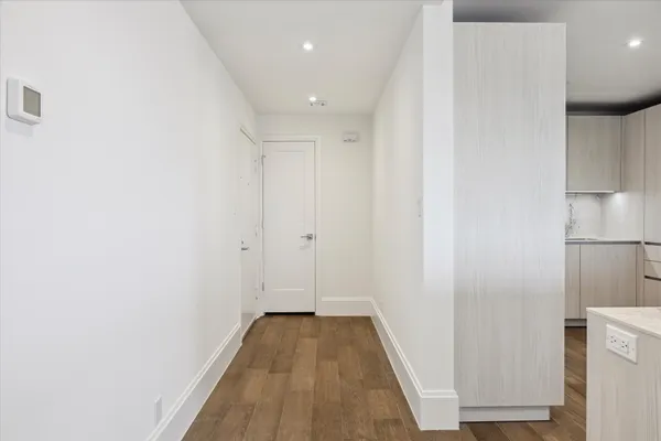 a view of a hallway with wooden floor and a bathroom