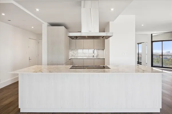 a large kitchen with stainless steel appliances kitchen island a large counter top a sink and a refrigerator