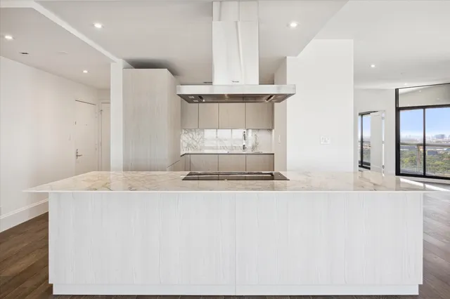 a large kitchen with stainless steel appliances kitchen island a large counter top a sink and a refrigerator