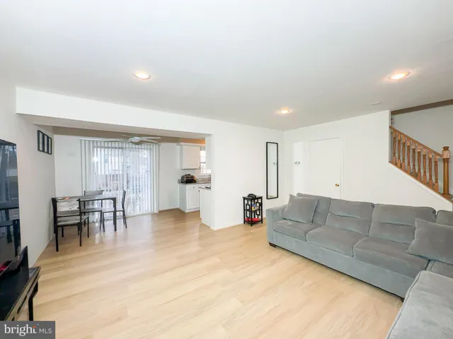 a living room with furniture and a dining table with wooden floor