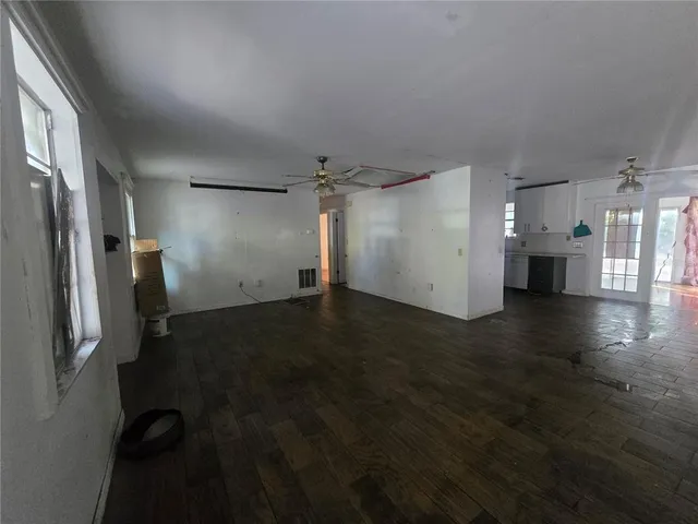 an empty room with wooden floor cabinets and a kitchen