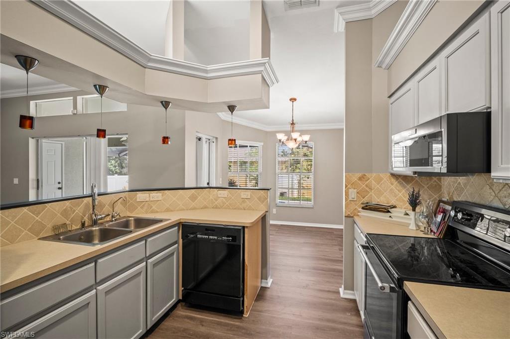 9061 Irving Road Fort Myers, FL 33967 - Photo 6 of 19 Kitchen featuring a sink, ornamental molding, a chandelier, dark wood finished floors, and stainless steel appliances
