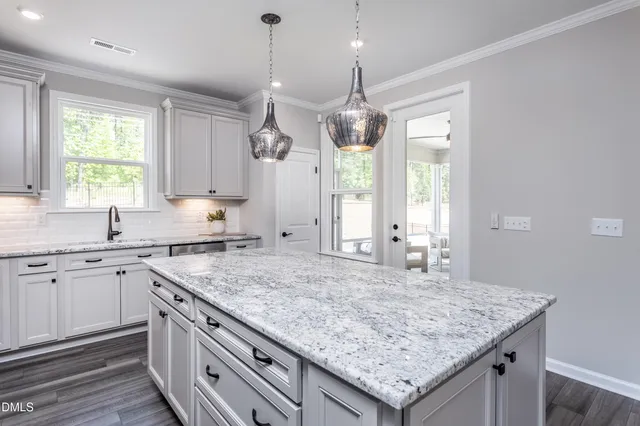 a kitchen with stainless steel appliances granite countertop a stove a refrigerator a kitchen island a sink and chairs