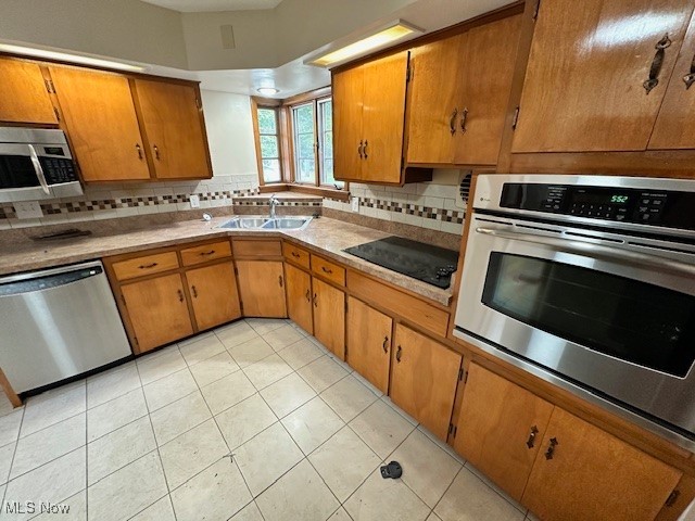 15959 Glynn Road Cleveland, OH 44112 - Photo 12 of 23 Kitchen featuring brown cabinetry, appliances with stainless steel finishes, and tasteful backsplash