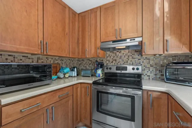 a kitchen with granite countertop a stove a sink and a microwave