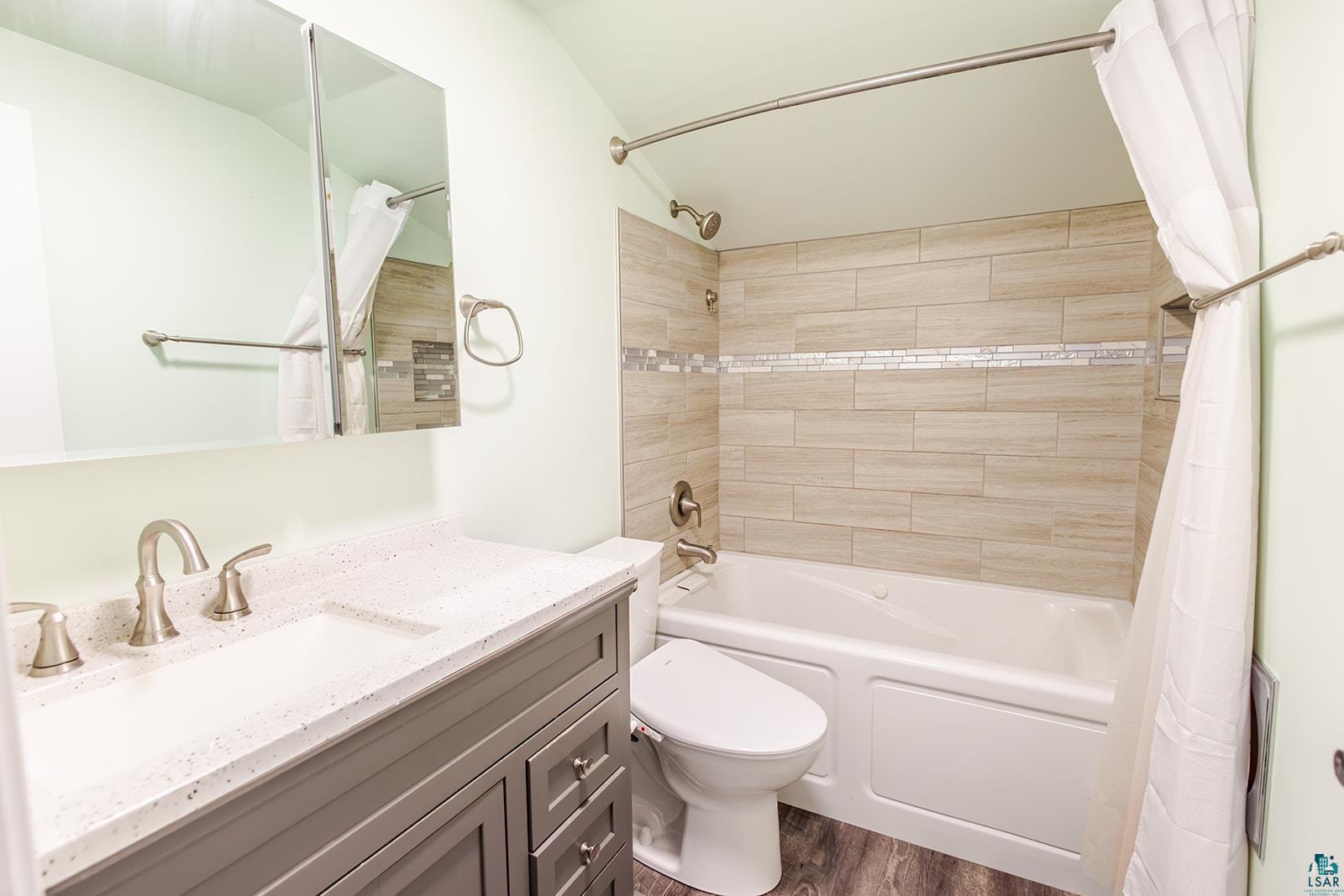 29 Ridge Road Esko, MN 55733 - Photo 24 of 41 Bathroom featuring a wood-finish floor, a gray vanity with a white speckled countertop, brushed nickel fixtures, and a medicine cabinet with mirrored doors