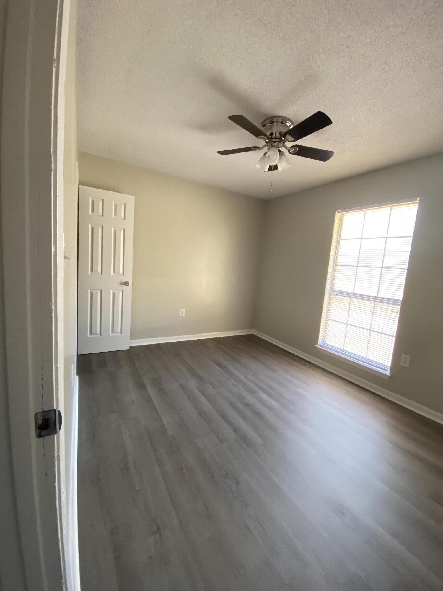 6173 Old Hickory Road Crestview, FL 32539 - Photo 16 of 22 an empty room with wooden floor chandelier fan and windows