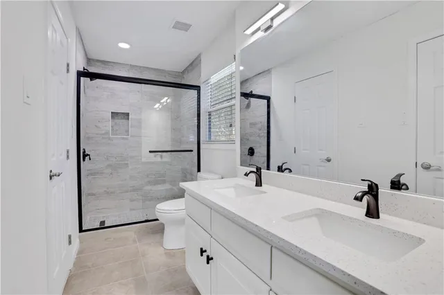 a bathroom with a double vanity sink toilet mirror and shower
