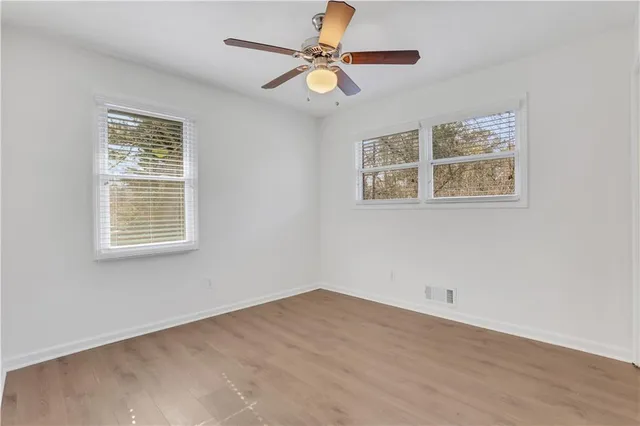 a view of an empty room with a window and wooden floor