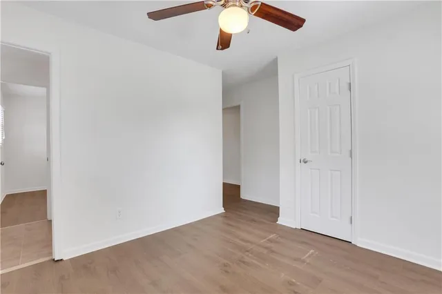 an empty room with wooden floor closet and windows