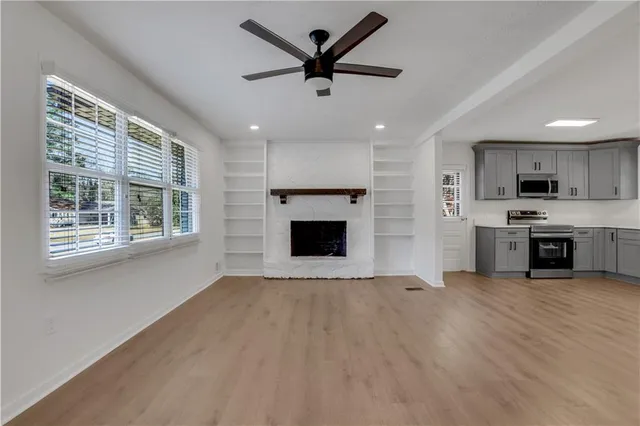 a view of a kitchen with a stove a kitchen island wooden floor and a ceiling fan