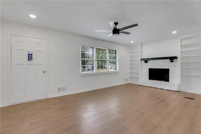 an empty room with windows fireplace and a ceiling fan