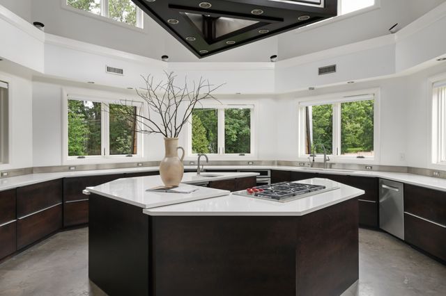 a front view of a kitchen with granite countertop a sink a stove a dining table and chairs