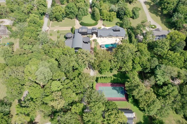 an aerial view of residential house with outdoor space and trees all around