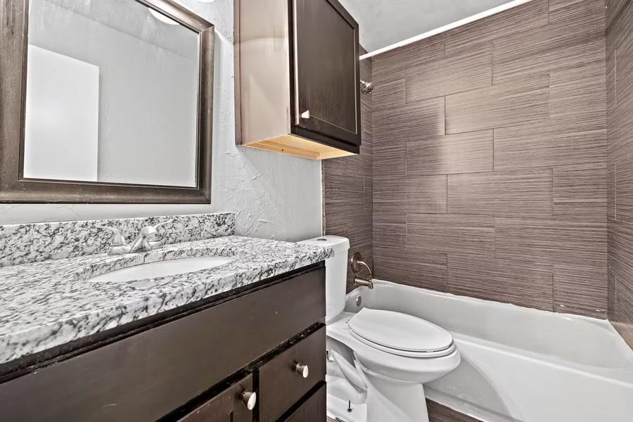 5414 Reiger Avenue, Unit 8 Dallas, TX 75214 - Photo 3 of 14 a bathroom with a granite countertop toilet a sink and a bathtub