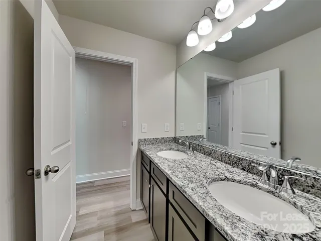 a bathroom with a granite countertop double vanity sink and a mirror