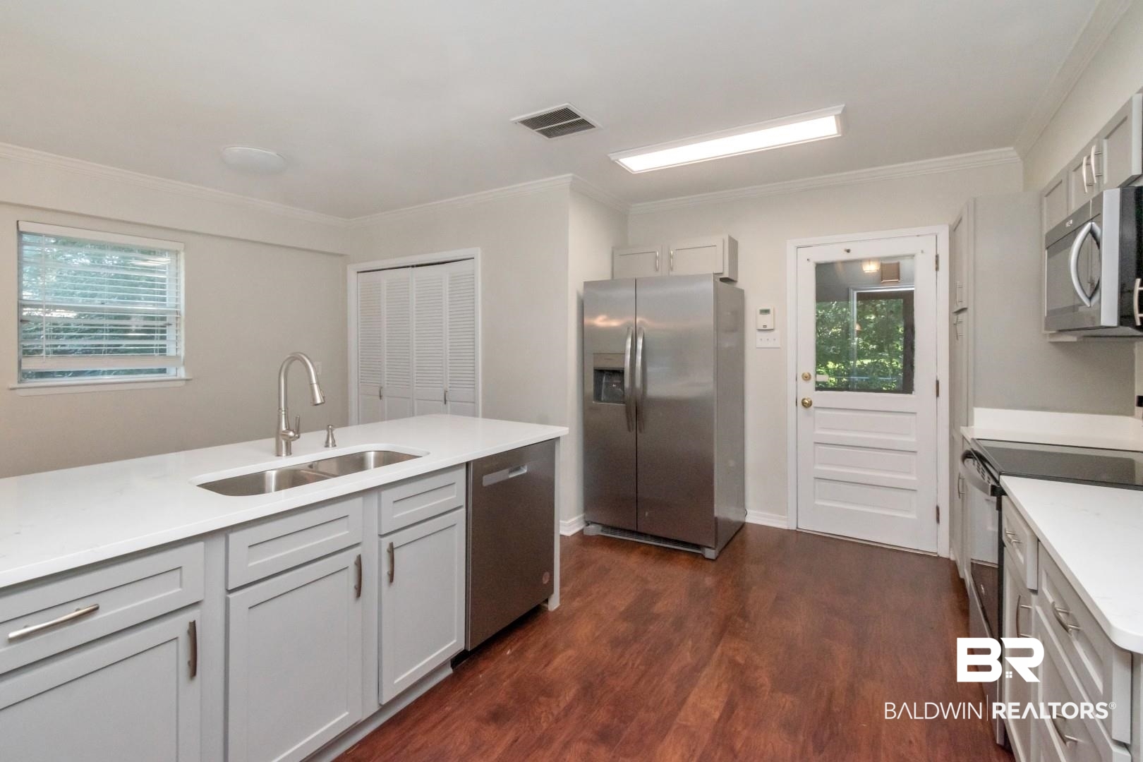 2105 Upham Court Mobile, AL 36607 - Photo 12 of 32 Kitchen featuring appliances with stainless steel finishes, dark wood-style flooring, light stone countertops, and ornamental molding