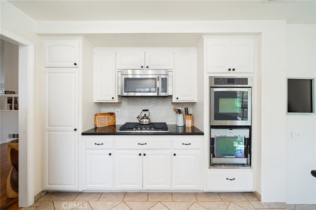 49 Pinewood, Unit 25 Irvine, CA 92604 - Photo 8 of 42 a kitchen with stainless steel appliances a sink a stove a microwave a refrigerator a cabinets and wooden floor