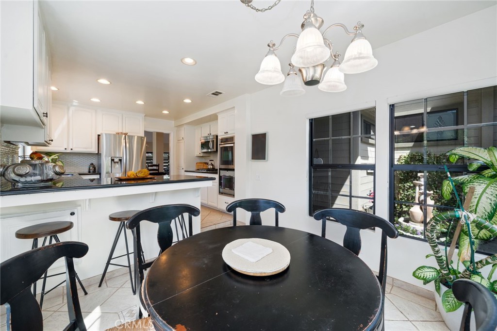 49 Pinewood, Unit 25 Irvine, CA 92604 - Photo 10 of 42 a kitchen with stainless steel appliances granite countertop a dining table chairs and a white refrigerator