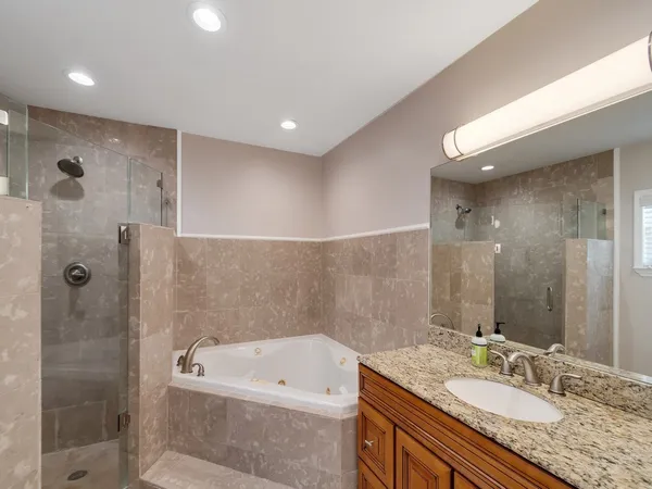 a bathroom with a granite countertop sink a mirror a bathtub and shower