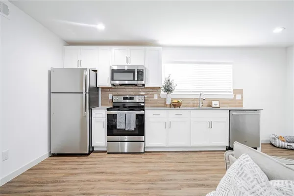 a kitchen with granite countertop a refrigerator stove top oven and sink