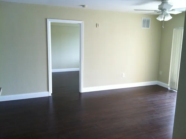an empty room with wooden floor and windows