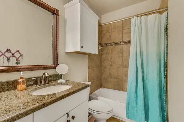 a bathroom with a granite countertop sink toilet and shower
