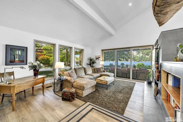 a living room with furniture hard wood floor and a floor to ceiling window