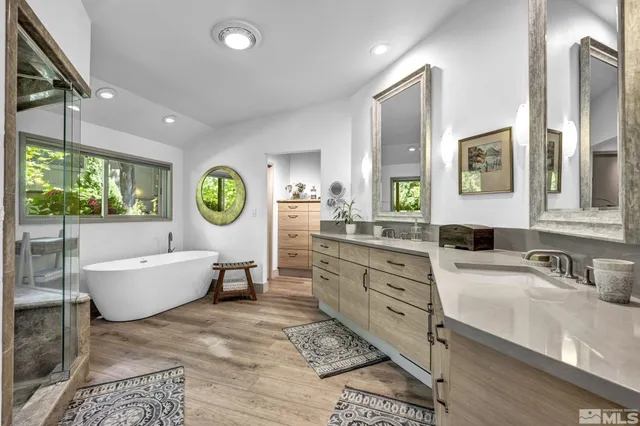 a bathroom with a granite countertop double vanity sink a mirror and a bathtub