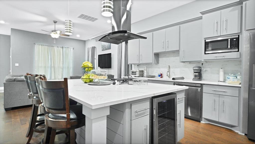 a kitchen with stainless steel appliances granite countertop a dining table chairs and a refrigerator