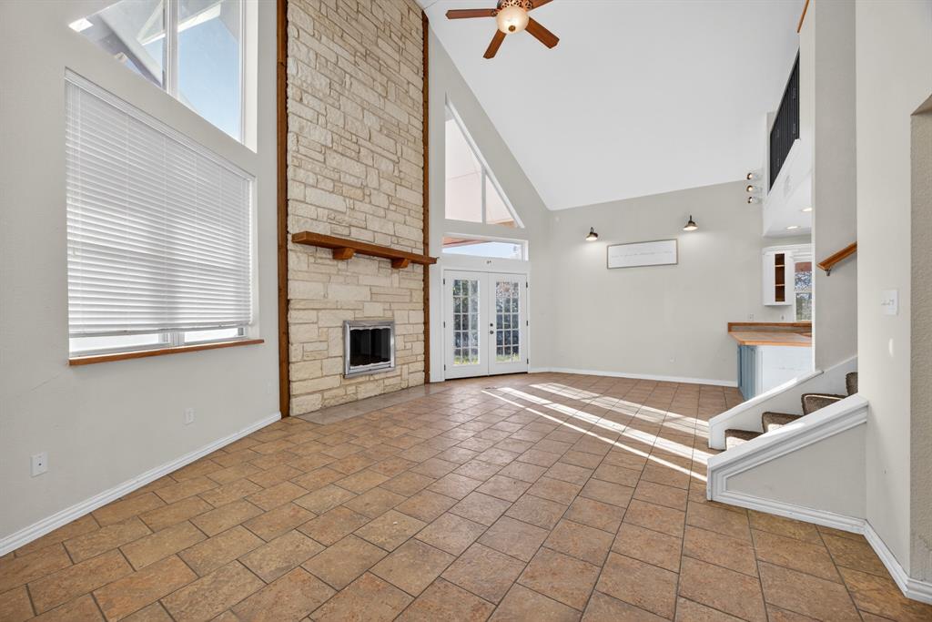 6775 Silver Creek Azle Road Azle, TX 76020 - Photo 7 of 40 Unfurnished living room with a stone fireplace, french doors, high vaulted ceiling, a ceiling fan, and stairs