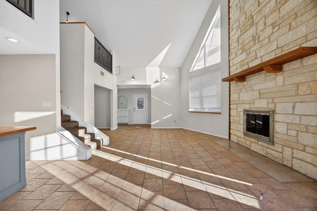 6775 Silver Creek Azle Road Azle, TX 76020 - Photo 8 of 40 Unfurnished living room featuring high vaulted ceiling, a fireplace, stone tile floors, and stairway