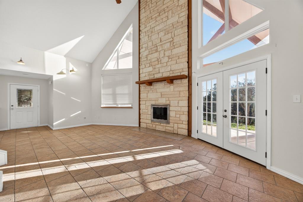 6775 Silver Creek Azle Road Azle, TX 76020 - Photo 9 of 40 Unfurnished living room featuring high vaulted ceiling, a fireplace, french doors, and healthy amount of natural light