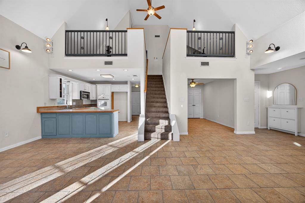6775 Silver Creek Azle Road Azle, TX 76020 - Photo 10 of 40 Unfurnished living room featuring stone tile flooring, a ceiling fan, stairs, high vaulted ceiling, and recessed lighting