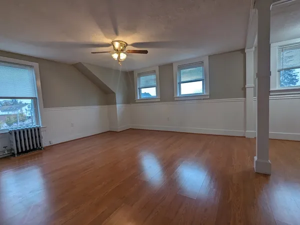 a view of an empty room with wooden floor and a window