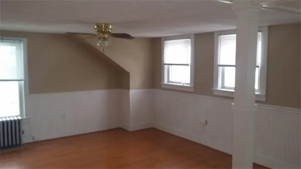 an empty room with windows and chandelier fan