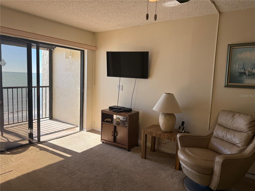 14950 Gulf Boulevard, Unit 805 Madeira Beach, FL 33708 - Photo 21 of 35 a living room with furniture a flat screen tv and a floor to ceiling window